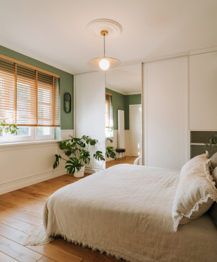 Duża sypialnia w stonowanych kolorach z białą szafą w zabudowie
