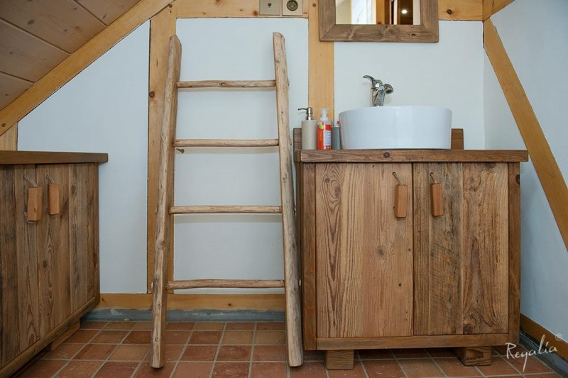 Łazienka na poddaszu z szafkami wykonanymi z drewnianych desek