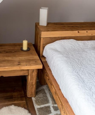 Sypialnia na poddaszu z meblami z drewna ciosanego