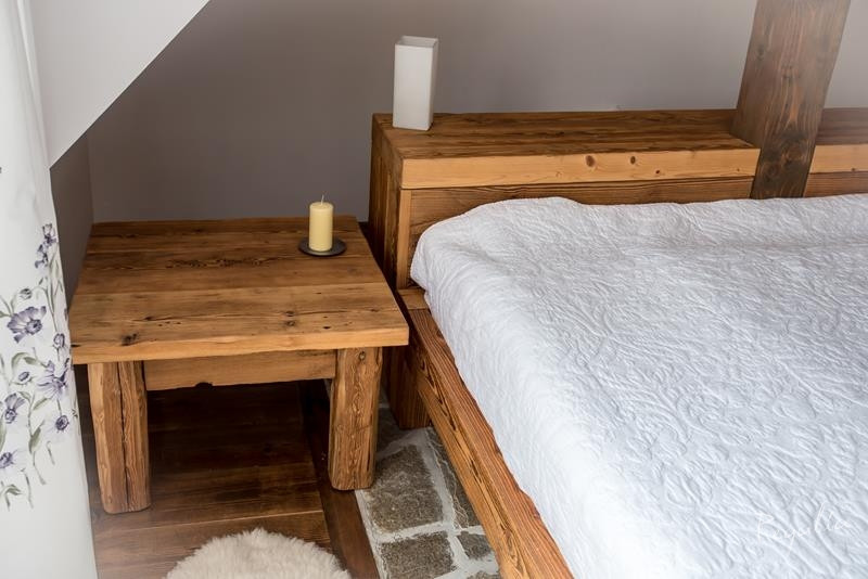 Sypialnia na poddaszu z meblami z drewna ciosanego