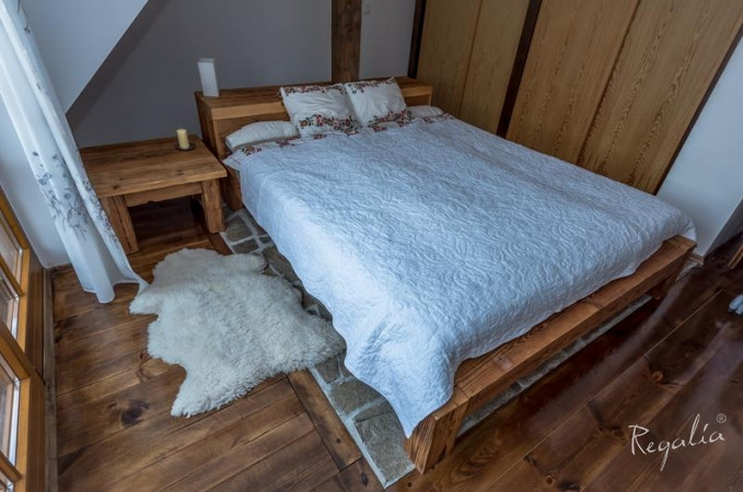 Sypialnia z drewnianym łóżkiem kontynentalnym, drewnianą szafą oraz drewnianą podłogą