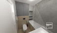 Projekt małej łazienki z zabudowaną wanną z szarymi kaflami płyt na ścianie