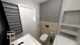 Mała łazienka z białą muszlą klozetową i czarną spłuczką montowaną w ścianie