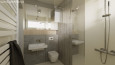 Łazienka z prysznicem oraz szarymi płytkami na ścianie
