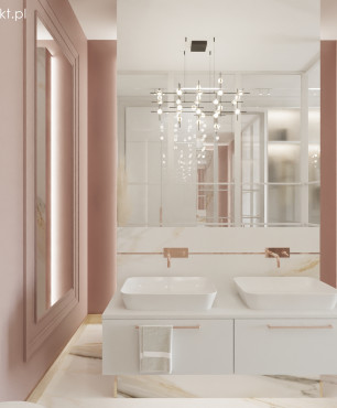 Łazienka z różowym kolorem ścian oraz białą szafką wiszącą