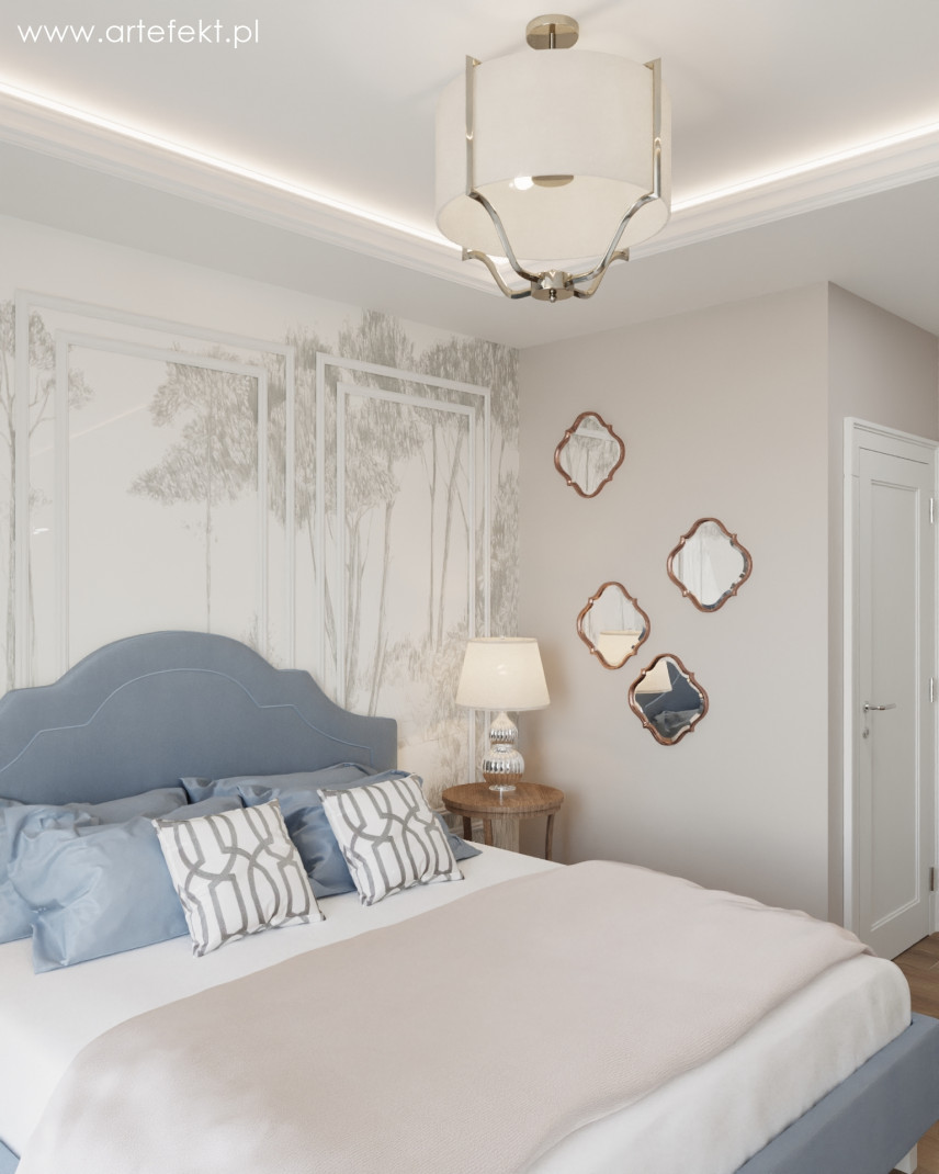 Przytulna sypialnia z błękitnym, tapicerowanym łóżkiem oraz tapetą z motywem lasu na ścianie