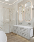 Łazienka z białymi, kamiennymi płytkami na ścianie oraz podwójnym eliptycznym lustrem