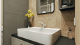 Łazienka z imitacją drewnianych płytek na ścianie oraz prostokątnym, ceramiczną umywalką nablatową