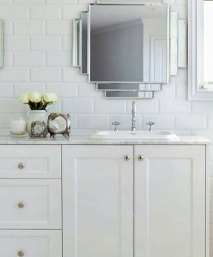 Łazienka z białymi płytkami na ścianie oraz białą szafką stojącą