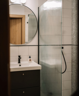 Mała łazienka z prysznicem oraz czarną szafką wiszącą z matowym frontem i z szufladami