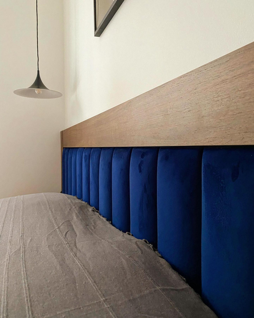 Sypialnia z dużym łóżkiem kontynentalnym z granatowym panelem tapicerowanym