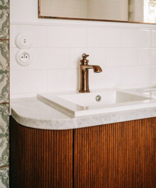 Łazienka z pięknym miedzianym kranem, umywalką podblatową oraz stylową, drewnianą szafką