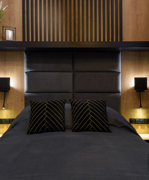 Sypialnia z drewnem ozdobnym na ścianie oraz z dużym łóżkiem kontynentalnym