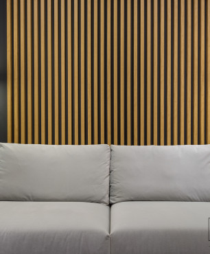 Salon z szarą sofą, czarnym kolorem ścian oraz lamelem drewnianym na ścianie