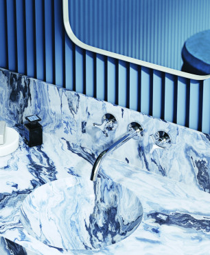 Łazienka z niebieskim kolorem ścian oraz kamiennym blatem ze zlewem podblatowym