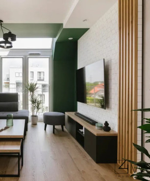 Salon z zielonym akcentem i białą tapetą na ścianie
