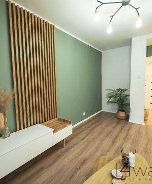 Salon z zielonym kolorem na ścianie oraz panelami na podłodze