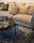 Klasyczny salon z wygodną, materiałową sofą, czarnym stolikiem kawowym oraz ciemnym dywanem