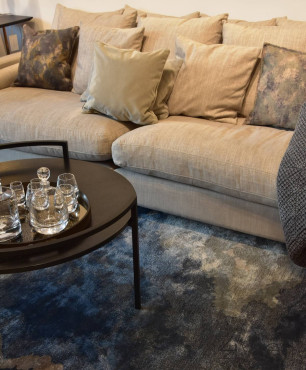 Klasyczny salon z wygodną, materiałową sofą, czarnym stolikiem kawowym oraz ciemnym dywanem