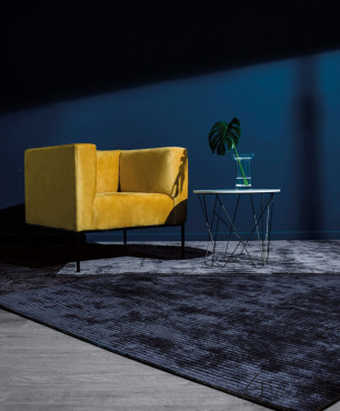 Salon z granatowym kolorem ścian oraz dywanem i żółtym, stylowym fotelem
