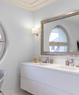 Łazienka z okrągłym oknem oraz z prostokątnym lustrem