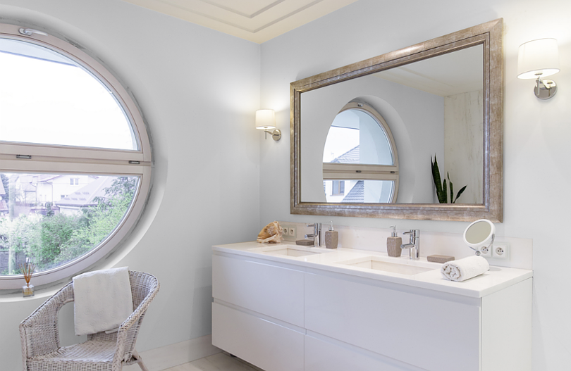Łazienka z okrągłym oknem oraz z prostokątnym lustrem