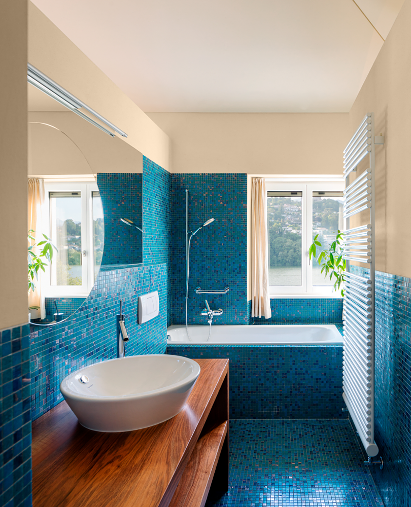 Wyjątkowa łazienka z oknem oraz wanną zabudowaną z niebieską mozaiką na ścianie i podłodze
