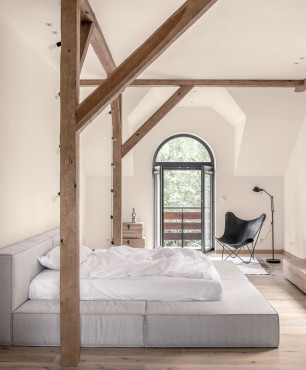 Sypialnia ze stropowymi belkami oraz łóżkiem kontynentalnym