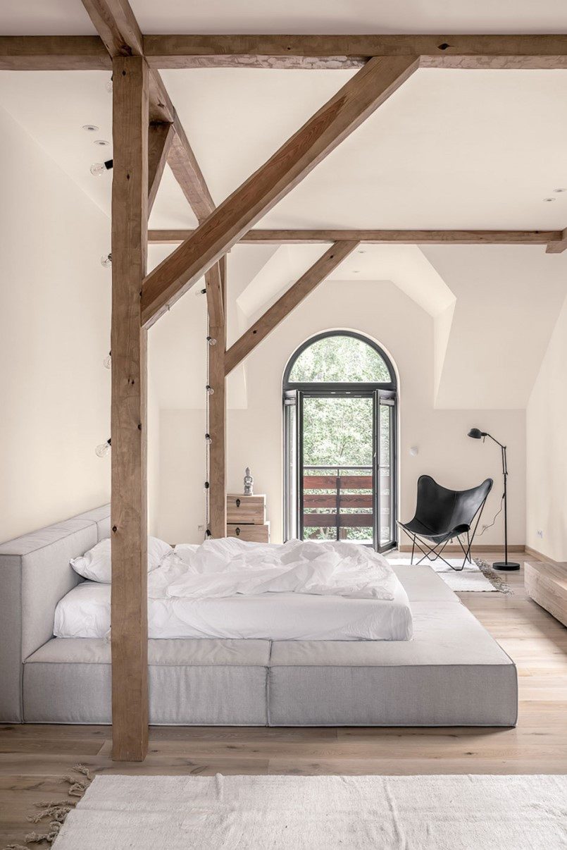 Sypialnia ze stropowymi belkami oraz łóżkiem kontynentalnym