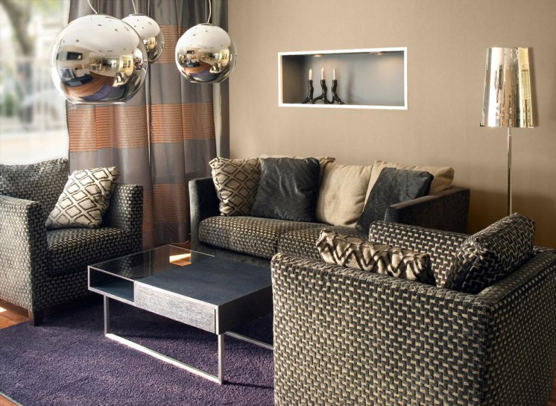Salon z jasnobrązowym kolorem na ścianie oraz piękną lampą wiszącą i stojącą