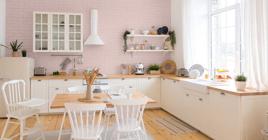 Kuchnia w stylu retro z różowym kolorem na ścianie oraz z meblami z białym frontem