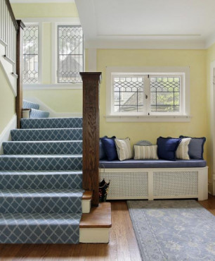 Klasyczny korytarz z drewnianymi schodami oraz żółtym kolorem ścian
