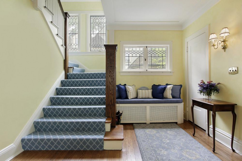 Klasyczny korytarz z drewnianymi schodami oraz żółtym kolorem ścian