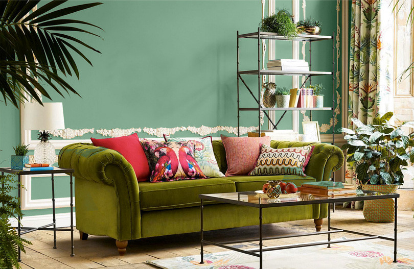 Salon z zielonym kolorem na ścianie oraz z zieloną, klasyczną sofą
