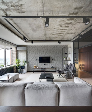 Salon z betonem architektonicznym na suficie oraz z dużym narożnikiem i jasnym dywanem na podłodze