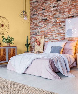 Zestawienie żółtego koloru i cegły na ścianie w sypialni