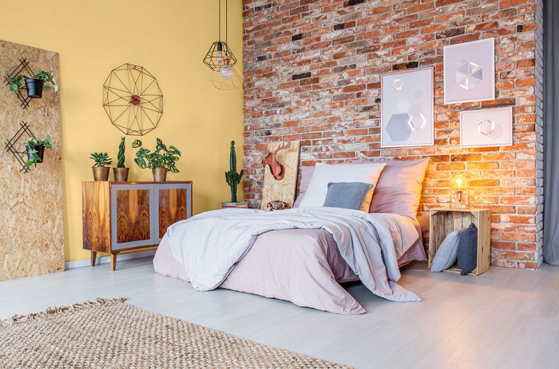 Zestawienie żółtego koloru i cegły na ścianie w sypialni