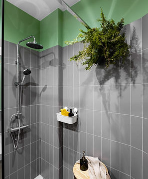 Łazienka z szarymi płytkami na ścianie połączonymi z zielonym kolorem farby