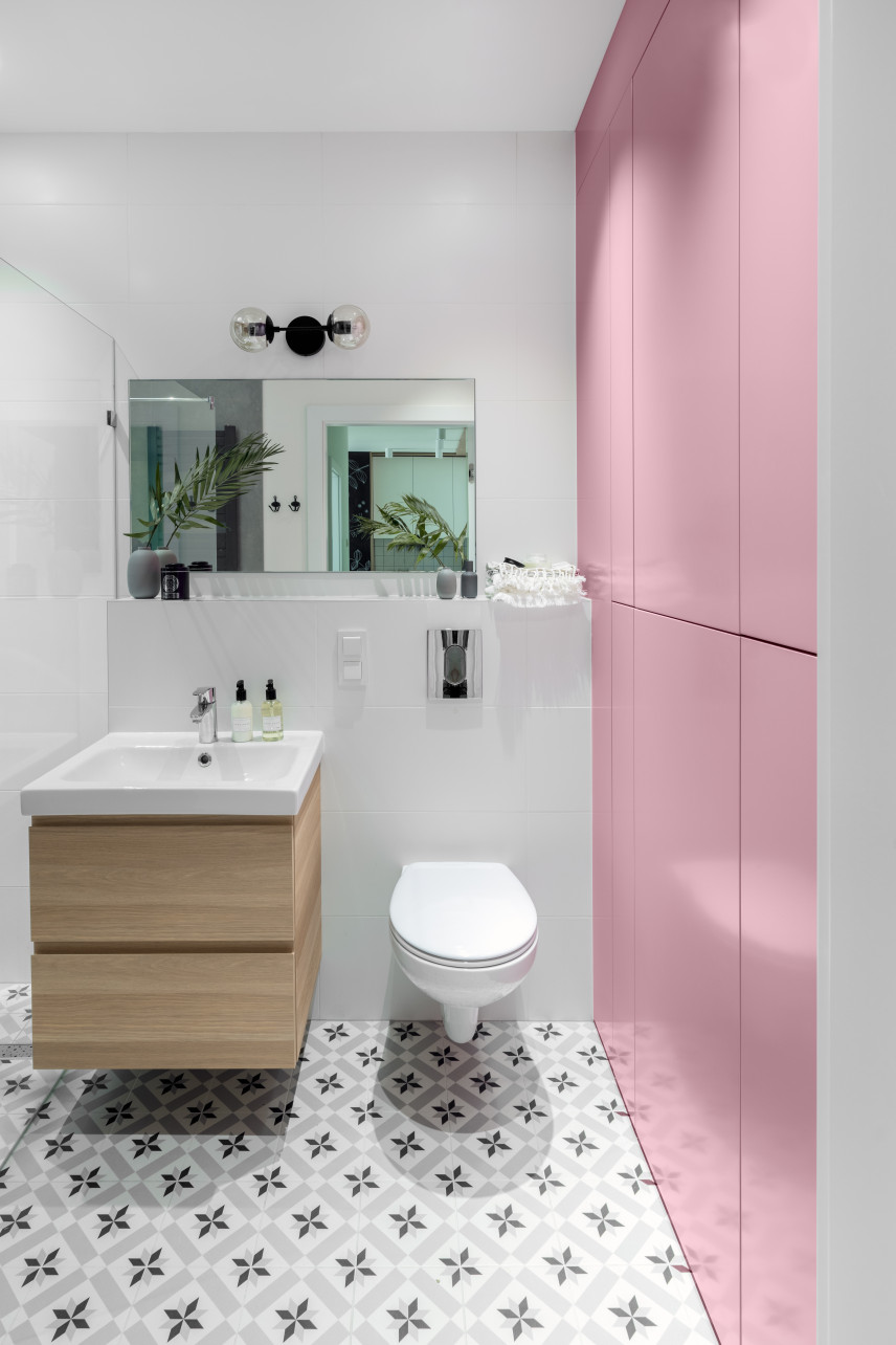 Łazienka z delikatnym kolorem różowym na ścianie oraz białą muszlą wiszącą