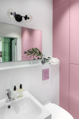 Łazienka z różowym kolorem na ścianie oraz z prostokątnym lustrem z kinkietem