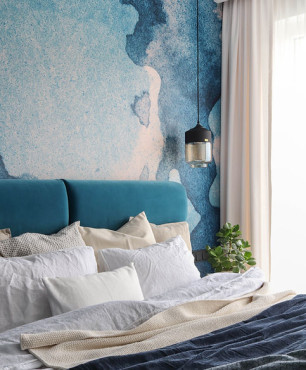 Sypialnia z niebieską tapetą na ścianie oraz dużym łóżkiem kontynentalnym