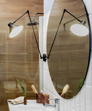Łazienka z okrągłym lustrem białymi i drewnianymi płytkami na ścianie