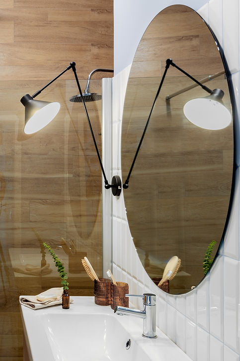 Łazienka z okrągłym lustrem białymi i drewnianymi płytkami na ścianie