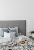 Sypialnia z białym kolorem ścian oraz szarym łóżkiem kontynentalnym