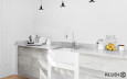 Kuchnia otwarta z białą cegłą na ścianie oraz białym zlewem podblatowym