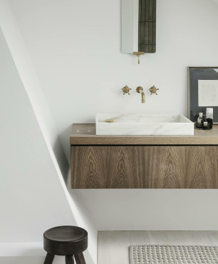 Łazienka z drewnianą szafką zamontowaną do ściany oraz białą, prostokątną umywalką nablatową