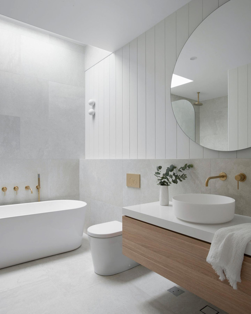 Duża, nowoczesna łazienka z owalną wanną oraz złotą armaturą, okrągłym lustrem i owalną umywalką nablatową