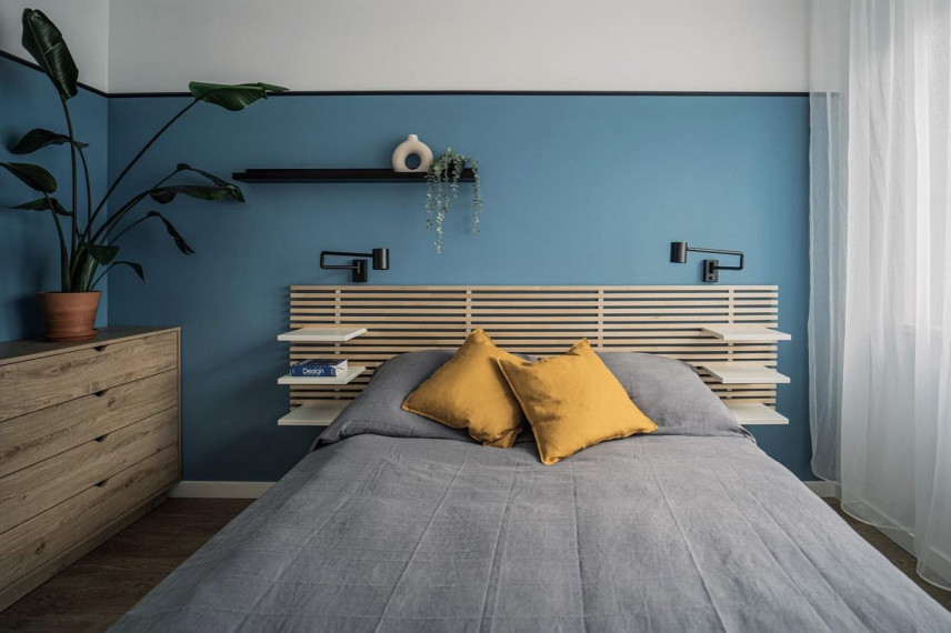 Sypialnia z niebieskim kolorem na ścianie oraz drewnianym łóżkiem i komoda z fornirowanymi frontami