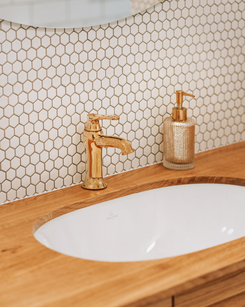 Łazienka z drewnianym blatem oraz owalną umywalką podblatową z płytkami na ścianie