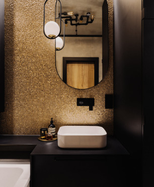 Klimatyczna łazienka z czarnymi płytkami na ścianie, przeplatanymi ze złotymi